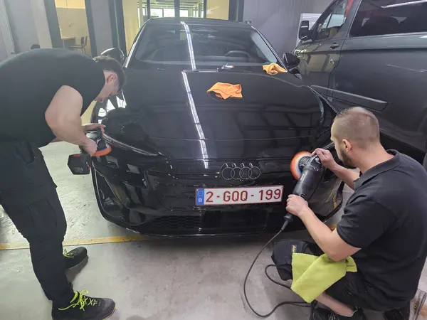 Deux participants polissent l’avant d’une voiture noire — Belgium Detailing Academy, formation automobile à Manage