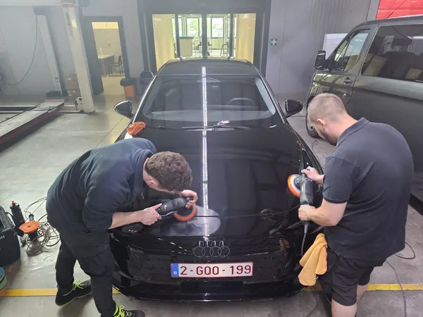Deux participants en exercice de polissage sur une voiture noire — Belgium Detailing Academy, formation automobile à Manage
