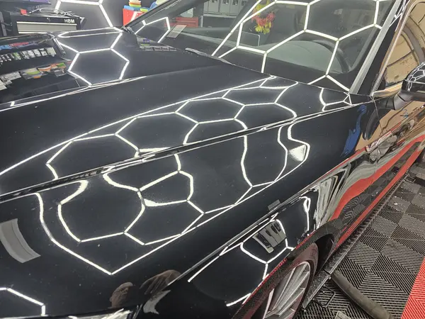Reflets de l’éclairage hexagonal sur une carrosserie sombre — Belgium Detailing Academy, formation automobile à Manage