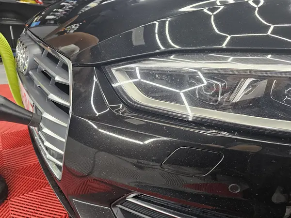 Face avant d’une voiture noire sous l’éclairage de contrôle — Belgium Detailing Academy, formation automobile à Manage