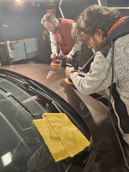 Deux personnes travaillent à la finition d’un capot — Belgium Detailing Academy, formation automobile à Manage